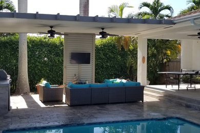 This is an example of a mid-sized contemporary backyard patio in Miami with an outdoor kitchen, concrete slab and a pergola.