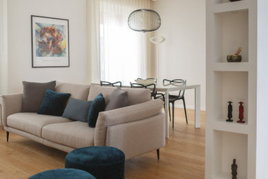 Esempio di un soggiorno moderno di medie dimensioni e aperto con pareti bianche, parquet chiaro e TV a parete