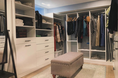 Modelo de armario vestidor unisex actual grande con armarios con paneles lisos, puertas de armario blancas, suelo de madera clara y suelo beige