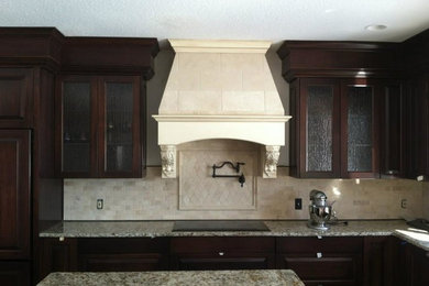 This is an example of a mid-sized l-shaped open plan kitchen in Minneapolis with glass-front cabinets, dark wood cabinets, granite benchtops, beige splashback, ceramic splashback and with island.