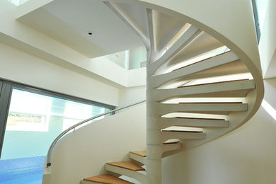 Diseño de escalera de caracol contemporánea con escalones de madera, contrahuellas de hormigón y barandilla de metal