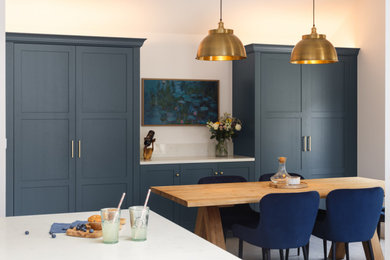 Inspiration for a medium sized modern l-shaped kitchen/diner in Other with a submerged sink, shaker cabinets, blue cabinets, quartz worktops, white splashback, black appliances, an island, grey floors and white worktops.