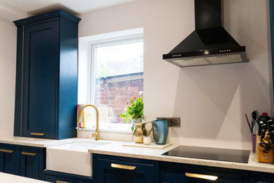 This is an example of a medium sized classic kitchen/diner in Other with a belfast sink, shaker cabinets, blue cabinets, quartz worktops, laminate floors, a breakfast bar and white worktops.