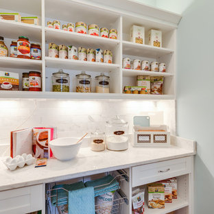 Cette photo montre une arrière-cuisine bord de mer en L avec un placard à porte shaker, des portes de placard blanches, une crédence blanche, un évier de ferme, une crédence en carrelage de pierre, un électroménager en acier inoxydable et un sol en bois foncé.