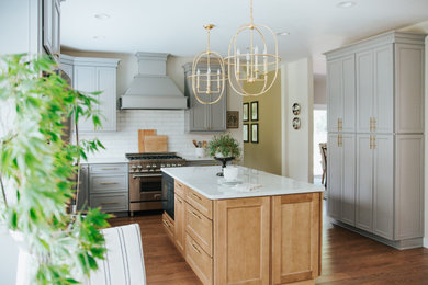 Inspiration for a mid-sized contemporary l-shaped medium tone wood floor and brown floor eat-in kitchen remodel in St Louis with an undermount sink, recessed-panel cabinets, gray cabinets, quartz countertops, white backsplash, subway tile backsplash, stainless steel appliances, an island and white countertops