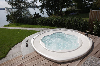 Design ideas for a mid-sized contemporary backyard custom-shaped aboveground pool in Berlin with a hot tub and decking.