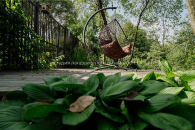 На фото: летний регулярный сад среднего размера на заднем дворе в классическом стиле с полуденной тенью и настилом с