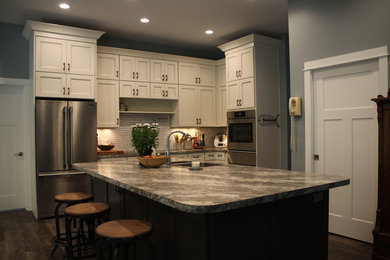 Example of a cottage brown floor kitchen design in Grand Rapids with a double-bowl sink, flat-panel cabinets, laminate countertops, stainless steel appliances and an island