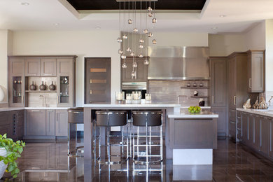 Kitchen - large transitional u-shaped kitchen idea in Denver with an undermount sink, recessed-panel cabinets, dark wood cabinets, quartzite countertops, gray backsplash, glass tile backsplash, stainless steel appliances and an island