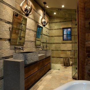 Example of a large mountain style master stone tile, beige tile and brown tile limestone floor and beige floor wet room design in Sacramento with flat-panel cabinets, dark wood cabinets, brown walls, a vessel sink, concrete countertops and a hinged shower door