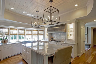 Large transitional u-shaped medium tone wood floor enclosed kitchen photo in Chicago with shaker cabinets, white cabinets, marble countertops, stainless steel appliances, an island, an undermount sink and gray backsplash