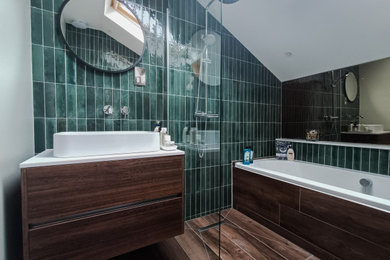 This is an example of a medium sized contemporary ensuite bathroom in Edinburgh with flat-panel cabinets, dark wood cabinets, a built-in bath, a wall mounted toilet, green tiles, ceramic tiles, green walls, porcelain flooring, a console sink, quartz worktops, brown floors, an open shower, white worktops, a feature wall, a single sink, a floating vanity unit and a vaulted ceiling.