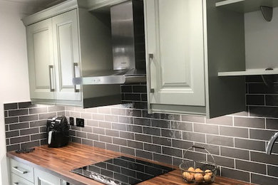 Design ideas for a medium sized galley enclosed kitchen in Essex with raised-panel cabinets, green cabinets, laminate countertops, porcelain splashback, stainless steel appliances, vinyl flooring, no island and grey floors.