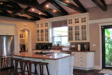 Example of a mid-sized transitional dark wood floor and brown floor kitchen design in Other with a farmhouse sink, shaker cabinets, white cabinets, marble countertops, beige backsplash, marble backsplash, stainless steel appliances and an island
