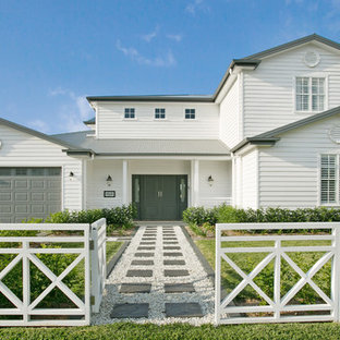 Photo of a country two-storey white house exterior in Gold Coast - Tweed with vinyl siding, a gable roof and a metal roof.