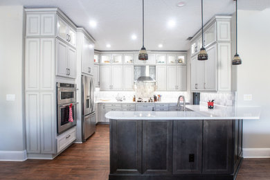 Inspiration for a mid-sized transitional u-shaped kitchen remodel in Orlando with an undermount sink, recessed-panel cabinets, white cabinets, quartz countertops, white backsplash, marble backsplash and beige countertops