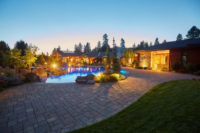 This is an example of an expansive contemporary back custom shaped natural swimming pool in Portland with with pool landscaping and concrete paving.