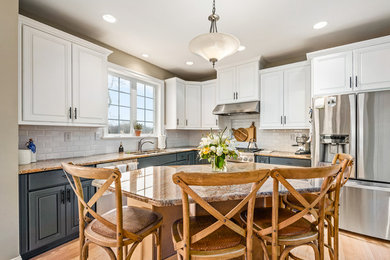 Mid-sized cottage l-shaped light wood floor and brown floor kitchen photo in Philadelphia with white cabinets, an undermount sink, raised-panel cabinets, granite countertops, white backsplash, subway tile backsplash, stainless steel appliances and an island