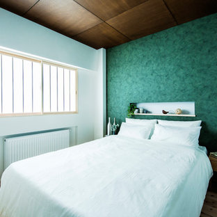 Foto di una camera da letto etnica con pareti verdi, pavimento in legno massello medio e pavimento marrone