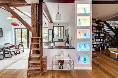 Inspiration pour une grande salle de séjour urbaine ouverte avec un bar de salon, un mur rose, un sol en bois brun, une cheminée standard, un manteau de cheminée en carrelage, un téléviseur fixé au mur et un sol beige.