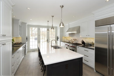 Minimalist brown floor eat-in kitchen photo with an integrated sink, yellow cabinets, quartzite countertops, white backsplash, stainless steel appliances, an island and black countertops