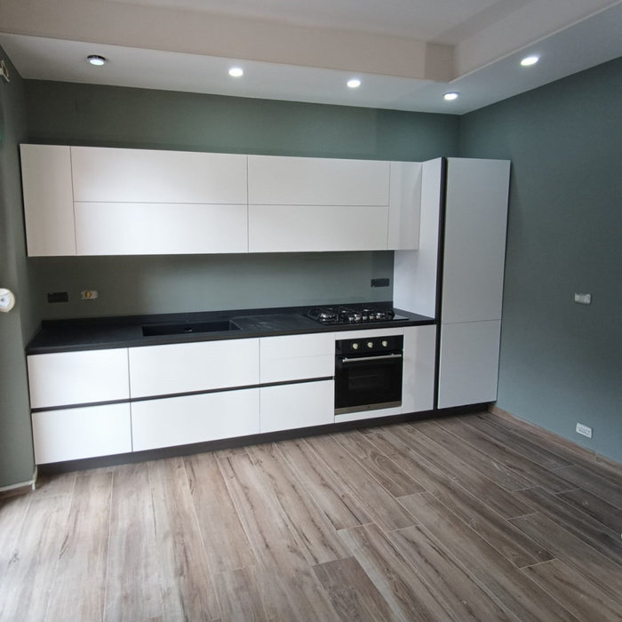 Cucina con anta Laccato Opaco Bianco e maniglia a gola Brunita. Top HPL finitura Pietra Nera con lavello 1 vascone SottoTop in Keratek Nero. Completano gli Elettrodomestici della MasterKitchen
