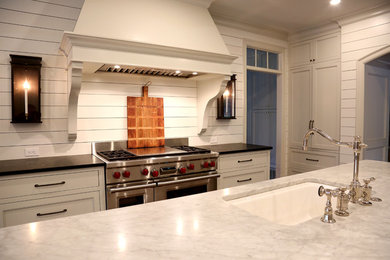 Example of a country dark wood floor and brown floor kitchen design in Charlotte with an undermount sink, shaker cabinets, white cabinets, marble countertops, white backsplash, wood backsplash, paneled appliances and two islands