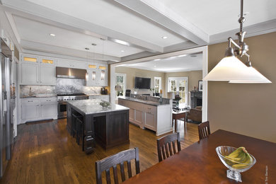 Elegant dark wood floor kitchen photo in Chicago with an undermount sink, shaker cabinets, white cabinets, soapstone countertops, gray backsplash, stone slab backsplash, stainless steel appliances and an island