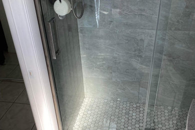 Imagen de cuarto de baño infantil moderno de tamaño medio con ducha esquinera, paredes grises, suelo con mosaicos de baldosas, suelo gris, ducha con puerta corredera y hornacina