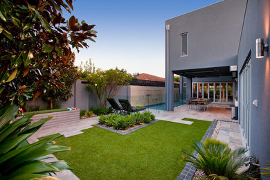 This is an example of a mid-sized contemporary backyard full sun formal garden in Perth with with pond and natural stone pavers.
