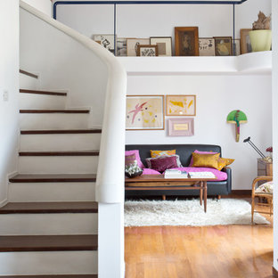 This is an example of a bohemian wood curved staircase in Naples with concrete risers.