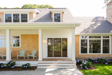 This is an example of a beach style two-storey white house exterior in Boston with wood siding, a gable roof and a mixed roof.