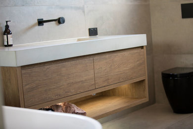 Modern bathroom in Sunshine Coast with light wood cabinets, gray tile, a trough sink and concrete benchtops.