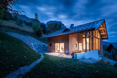 Aménagement d'une grande façade de maison beige contemporaine en bois à un étage avec un toit à deux pans et un toit en métal.