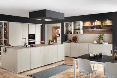 Design ideas for a medium sized scandi cream and black l-shaped kitchen/diner in Other with a single-bowl sink, recessed-panel cabinets, distressed cabinets, quartz worktops, beige splashback, glass sheet splashback, integrated appliances, laminate floors, an island, brown floors, beige worktops and a feature wall.