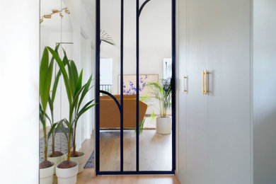 This is an example of a scandi foyer in Lille with white walls, light hardwood flooring, a black front door and beige floors.