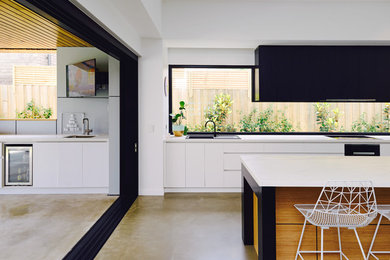 Photo of a large contemporary open plan kitchen in Geelong with a single-bowl sink, white cabinets, quartz benchtops, window splashback, concrete floors, with island and grey floor.