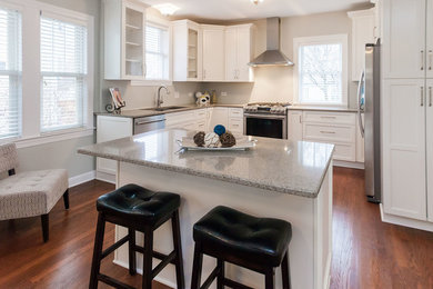 Inspiration for a mid-sized transitional u-shaped open plan kitchen in Chicago with a double-bowl sink, recessed-panel cabinets, white cabinets, granite benchtops, stainless steel appliances, dark hardwood floors, with island and brown floor.