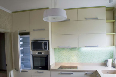 Foto di una cucina a L design chiusa e di medie dimensioni con lavello integrato, ante lisce, ante beige, top in superficie solida, elettrodomestici in acciaio inossidabile, nessuna isola e top beige