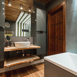 Idée de décoration pour une salle de bain principale design avec un placard sans porte, un combiné douche/baignoire, un carrelage gris, un sol en bois peint, une vasque, un sol marron et un plan de toilette en bois.