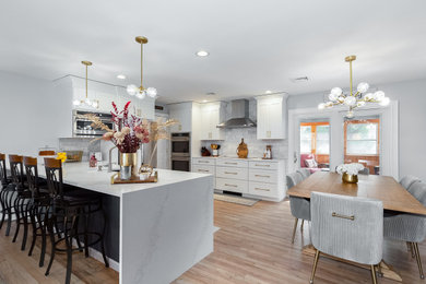 Inspiration for a mid-sized timeless u-shaped light wood floor and brown floor eat-in kitchen remodel in New York with an undermount sink, shaker cabinets, white cabinets, quartz countertops, gray backsplash, marble backsplash, stainless steel appliances, a peninsula and white countertops