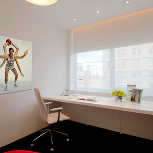 Inspiration for a modern home office and library in New York with a built-in desk and black floors.