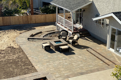 Huge minimalist concrete paver back porch idea in San Luis Obispo with a fire pit
