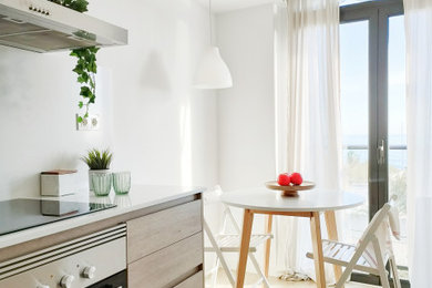 This is an example of a small scandi enclosed kitchen in Barcelona with flat-panel cabinets, medium wood cabinets, engineered stone countertops, stainless steel appliances, light hardwood flooring, no island, brown floors and white worktops.