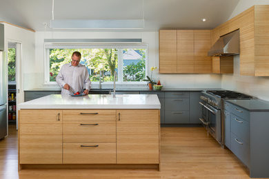 Inspiration for a mid-sized contemporary u-shaped eat-in kitchen in Minneapolis with an undermount sink, medium wood cabinets, quartz benchtops, white splashback, glass tile splashback, stainless steel appliances, light hardwood floors and with island.