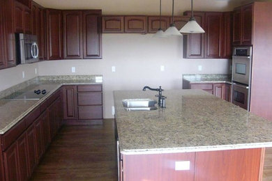Inspiration for a large country u-shaped dark wood floor open concept kitchen remodel in Denver with a double-bowl sink, recessed-panel cabinets, dark wood cabinets, granite countertops, stainless steel appliances and an island