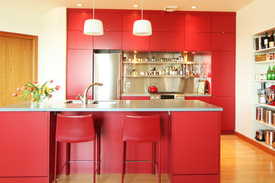 Open concept kitchen - small modern medium tone wood floor open concept kitchen idea in Other with an undermount sink, flat-panel cabinets, red cabinets, solid surface countertops, metal backsplash, stainless steel appliances and an island