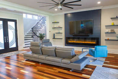 This is an example of a mid-sized modern open concept living room in Charlotte with grey walls, light hardwood floors, a ribbon fireplace, a tile fireplace surround, a wall-mounted tv and multi-coloured floor.