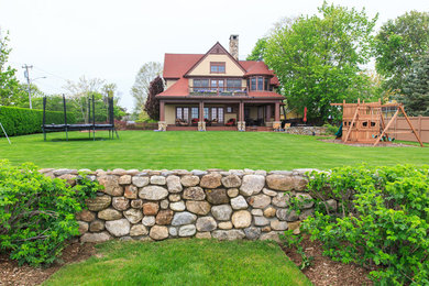 This is an example of a large craftsman full sun backyard retaining wall landscape in New York with decking for summer.
