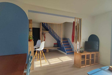 Inspiration pour un salon marin ouvert avec un mur bleu, parquet clair, un téléviseur indépendant et un escalier.